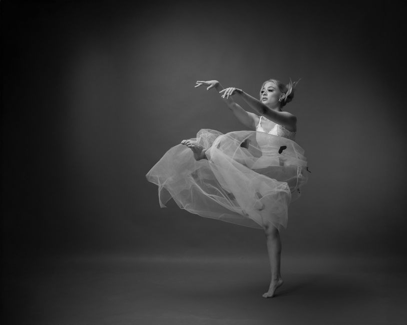 Black and white image of a contemporary ballet dancer in flowing dress, captured mid-movement.